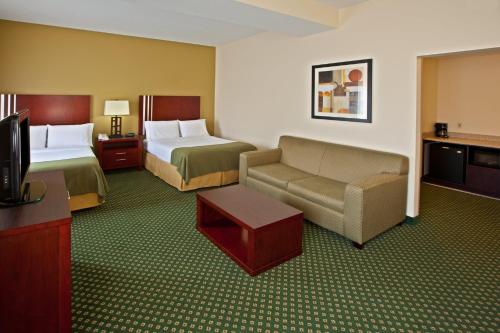 a hotel room with two beds and a couch and a tv at Holiday Inn Express & Suites Indianapolis - East by IHG in Indianapolis
