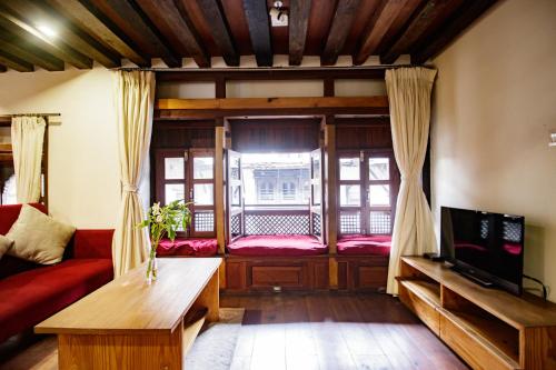 a living room with a red couch and a window at The Newari dream in Old Patan-high ceiling & charm in Pātan