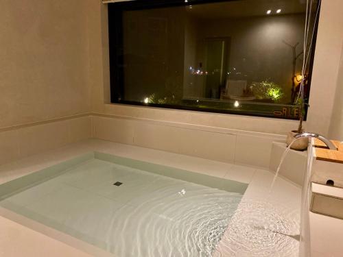 a bathroom with a bath tub with a window at 오를 Orle in Kama-ri
