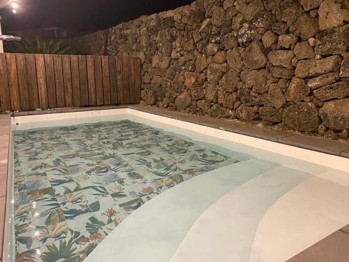 a swimming pool with a tile floor in front of a stone wall at 오를 Orle in Kama-ri