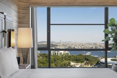a bedroom with a large window with a view of the city at Hilton Istanbul Bosphorus in Istanbul