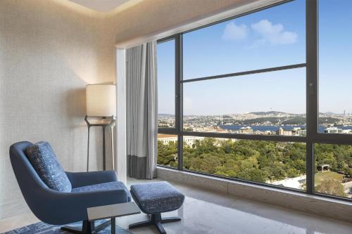 a room with a blue chair and a large window at Hilton Istanbul Bosphorus in Istanbul