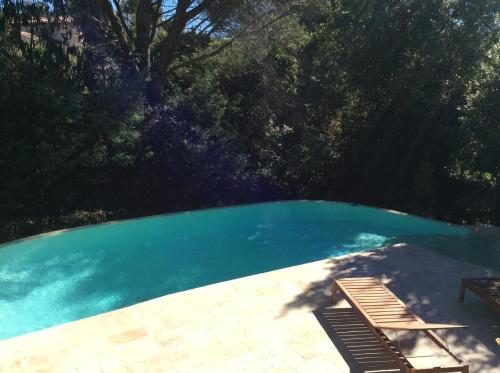 une grande piscine avec une terrasse et un banc dans l'établissement Villa Mareste, à Grimaud