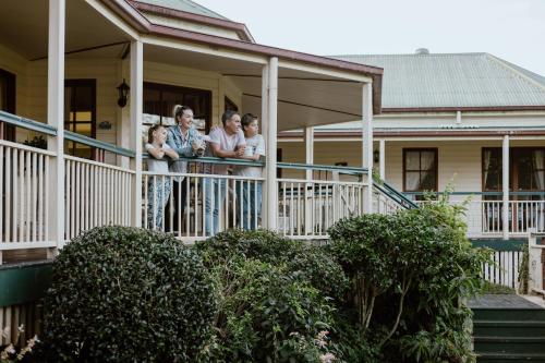 a family standing on the porch of a house at Grand Queenslander for Large Groups 5 mins to Maleny and Montville in Balmoral Ridge