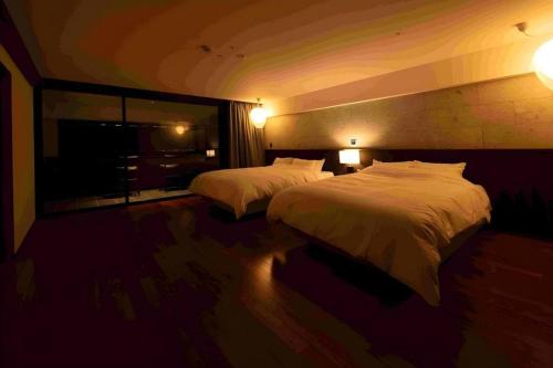 a hotel room with two beds and a large window at Kannawa Onsen Hotel Sansuikan in Beppu