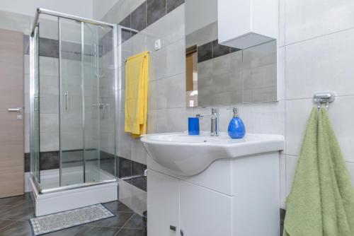 Un baño blanco con lavabo y ducha. en Apartments Bava, en Trogir