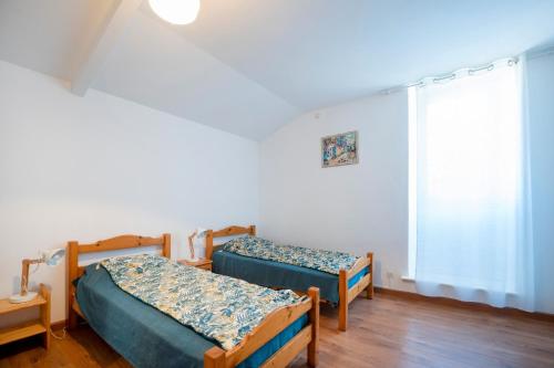 two beds in a room with a window at Gite de charme aux portes du Gers in Lagrange