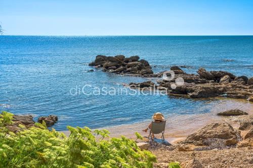 a person sitting in a chair on the beach at Gadir in Terrauzza