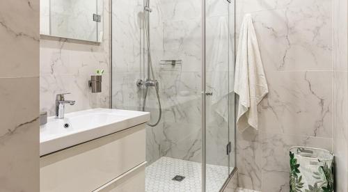 a white bathroom with a shower and a sink at Lotus Hotel Tashkent in Yakkasaray