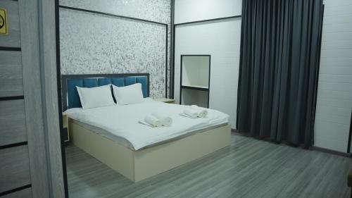 a bedroom with a bed with white sheets and a mirror at Lotus Hotel Tashkent in Yakkasaray