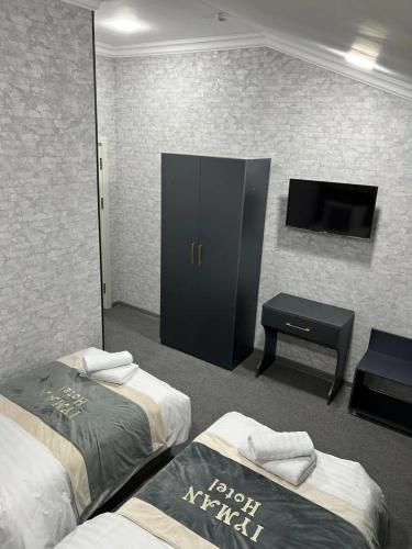a hotel room with two beds and a tv at Lotus Hotel Tashkent in Yakkasaray