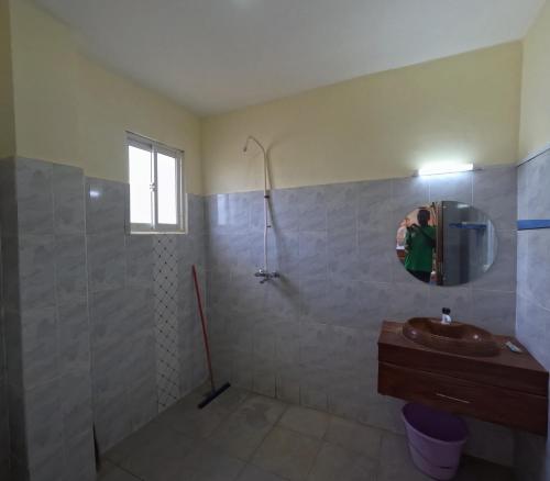 a person taking a picture of a bathroom with a shower at Haven Homes one bedroom in Diani Beach