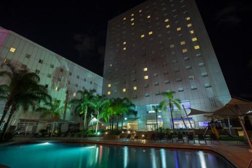 a large building with a pool in front of it at night at Novotel Monterrey Valle in Monterrey