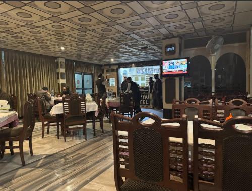 a dining room with tables and chairs and televisions at Roopyal Hotel & Restaurant in Dargai