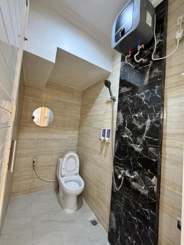 a bathroom with a toilet and a tv on the wall at Villa dina in Songgoriti