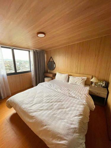 a bedroom with a large white bed with wooden walls at Lina Hotel in Khu Chi Lăng