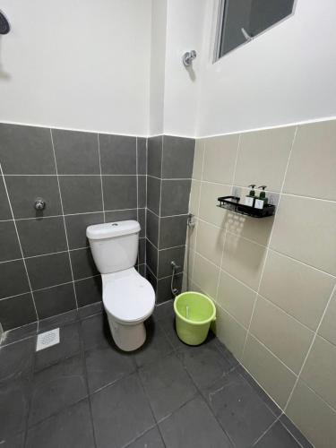 a bathroom with a toilet and a green bucket at D'Haira Homestay Port Dickson Mu5lim Only in Port Dickson
