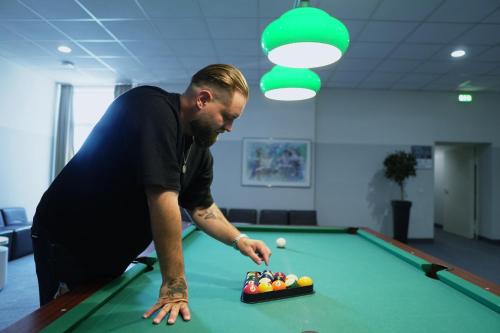 a man playing pool with a tray of balls on a pool table at B&K Hotels in Vlotho