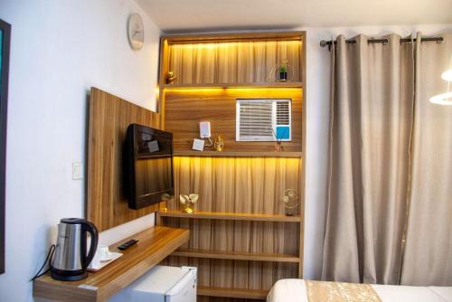 a room with a bed and a desk with a television at Ontario Suites in Lagos