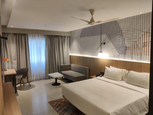 a hotel room with a bed and a chair at Hotel Manorama Vijayawada in Vijayawāda