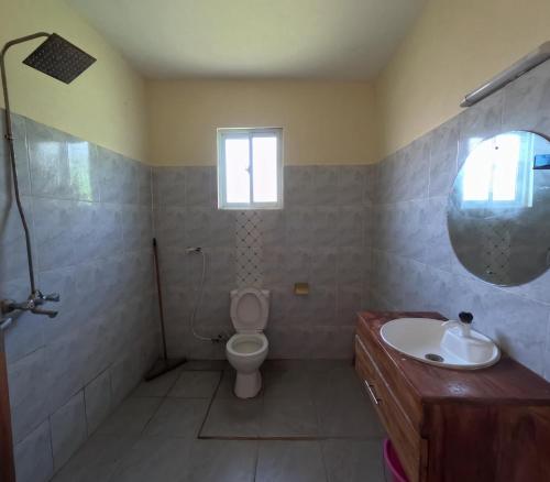 Un baño con inodoro, lavabo y ventana. en Haven Homes Studio Apartment, en Diani Beach