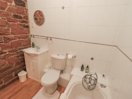 a bathroom with a toilet and a sink and a bath tub at The Hayloft in Wigton