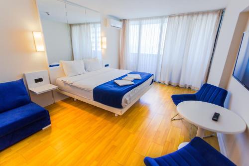 a bedroom with a bed and two blue chairs at Glorious Sea View Aparthotel In Orbi City Batumi in Batumi