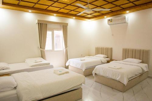 a room with three beds and a window at Darunique Inn in Nizwa