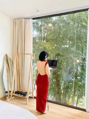 a woman standing in front of a window with a laptop at Dreamy Homestay Tam Đảo in Tam Ðảo