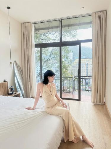 a woman in a dress sitting on a bed at Dreamy Homestay Tam Đảo in Tam Ðảo