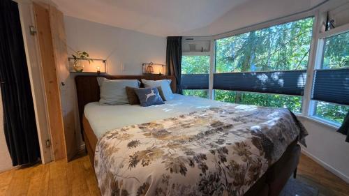 una camera da letto con un letto grande in una stanza con finestre di Cozy forest cottage in quiet nature reserve a Emst