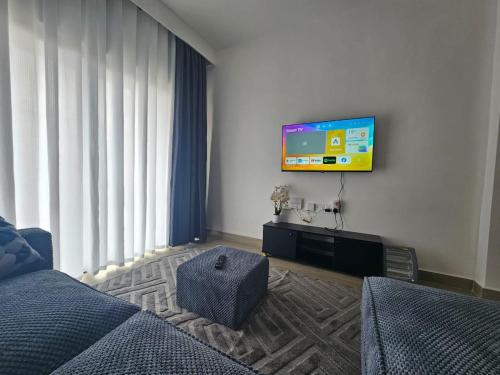 a living room with a bed and a tv on the wall at Serenity stay Kilimani in Nairobi