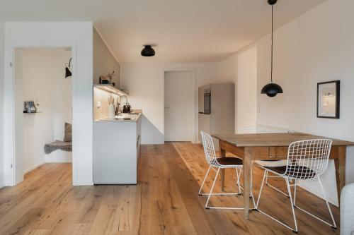 a kitchen and dining room with a wooden table and chairs at HØV - Boutique-Apartments im Allgäu - Rückzug & Design in Altusried