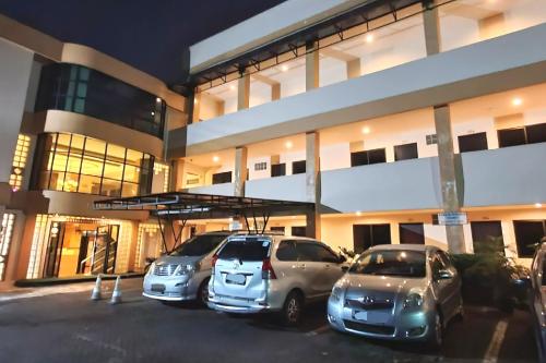 ジャカルタにあるJambrut Innの建物前の駐車場に駐車した車2台