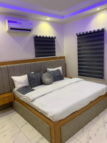 a large bed in a room with a window at Less2More Luxury Suites in Agege