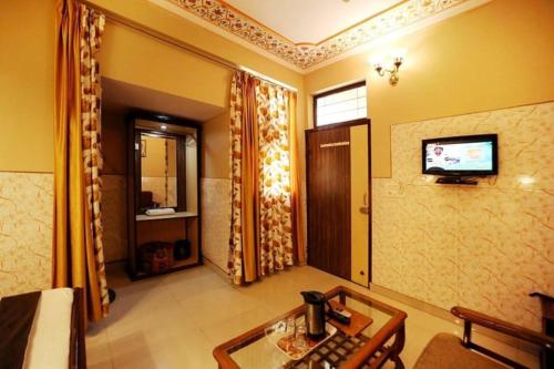 斋浦尔Joey's Hostel的客厅配有桌子和墙上的电视