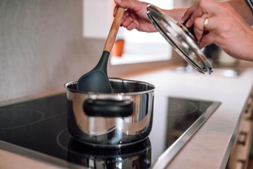 a person stirring a pot on a stove with a spoon at Schmidtburger Hof in Weiler