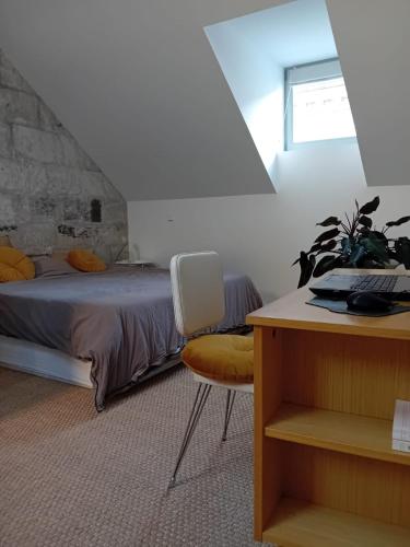 Tiny, bright architect-designed loft, king size في سوموور: غرفة نوم بها سرير ومكتب وكرسي