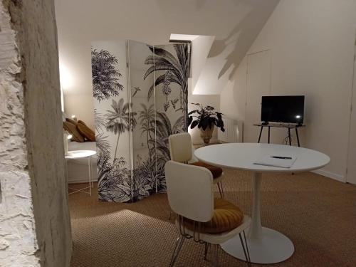 Tiny, bright architect-designed loft, king size في سوموور: غرفة بها طاولة وكراسي وتلفزيون