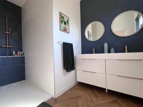 ein Badezimmer mit einem weißen Waschtisch und zwei Spiegeln in der Unterkunft Superbe villa avec piscine in Castelnau-le-Lez