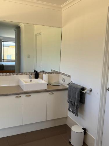 a white bathroom with a sink and a mirror at The Lux Dip in Perth