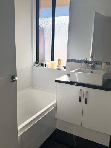 a white bathroom with a sink and a bath tub at The Lux Dip in Perth