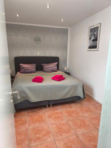 a bedroom with a bed with two red pillows on it at Appartementhaus Strandnähe in Warnemünde