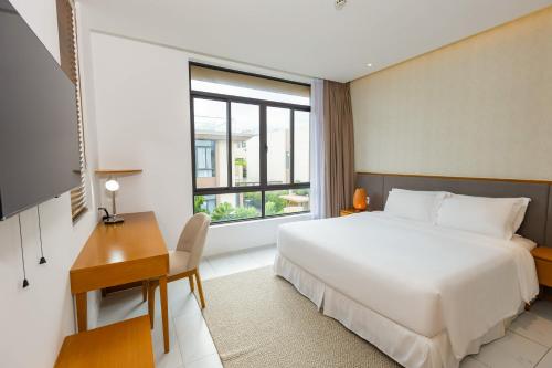 ein Hotelzimmer mit einem Bett, einem Schreibtisch und einem Fenster in der Unterkunft Ocean Breeze Villa Cam Ranh in Cam Ranh