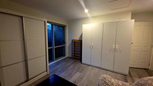 オークランドにあるQuiet 40m Studio - Kitchen, Washer, AC, Work Deskの白いキャビネットと窓が備わる客室です。