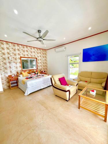 a bedroom with a bed and a couch and a table at Villa Chez Batista in Takamaka