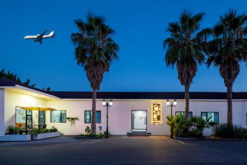 an airplane is flying over a building with palm trees at Qiyunju Hotel-24H Free Airport Pickup Drop-off in Shanghai