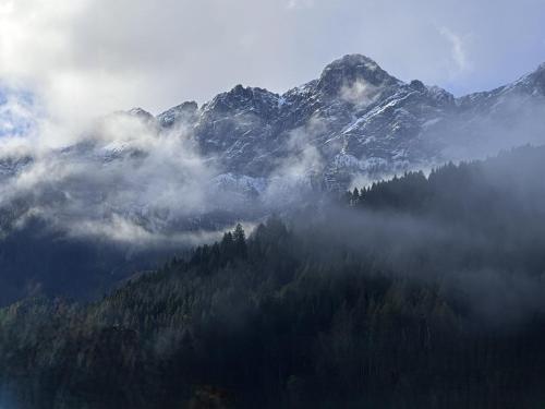 an aerial view of a mountain with clouds and trees at Aparthotel Familiaris - Family Apartments - Pools & Spa in Dolomites in Valdaora
