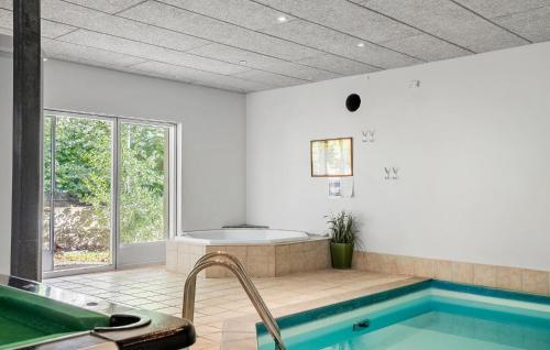 uma casa de banho com uma banheira e uma piscina em Gorgeous Home In Haderslev With Sauna em Årøsund