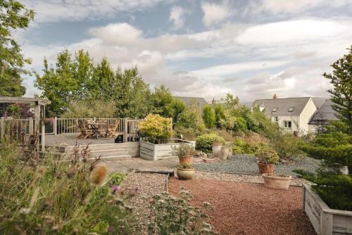 a garden with a wooden deck with potted plants at Glen Bank in Bampton